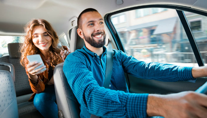 Smiling taxi driver with a female passenger in the back seat