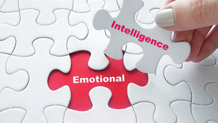 Close-up of a woman's hand placing the final piece of a puzzle that says 'emotional intelligence'