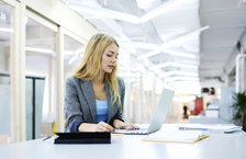 A young woman typing on a laptop in an office