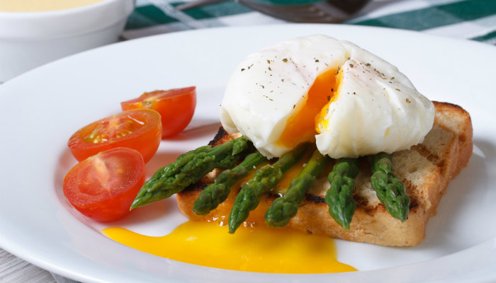 Poached egg on toast with asparagus and tomatoes