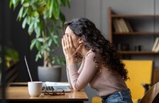 anxious female worker unproductive sitting at desk with laptop in despair