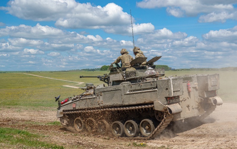 Tank crew sitting on top of a moving tank