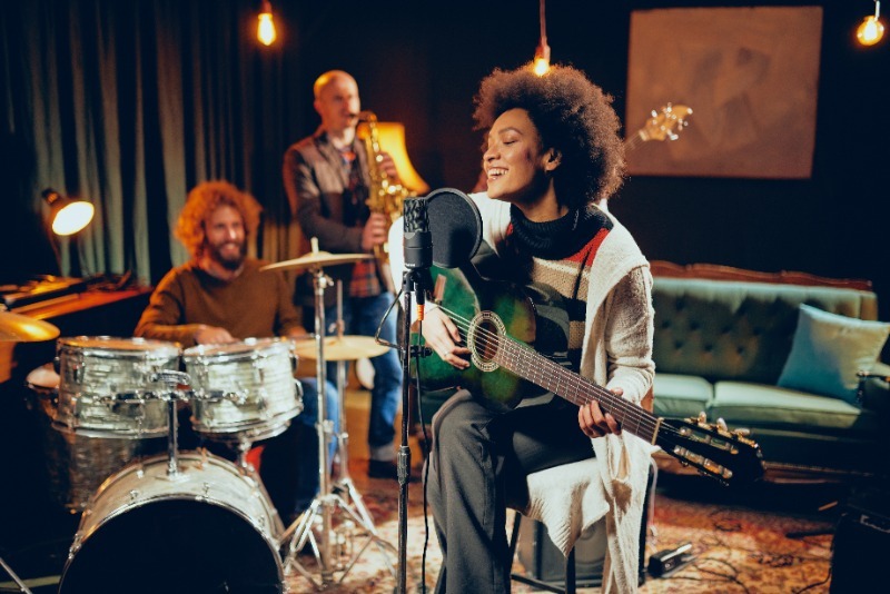 Musician holding a guitar and singing into a micriphone